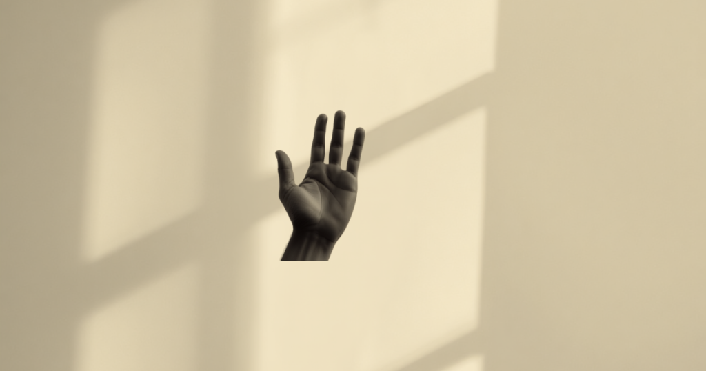 Mão levantada em um gesto calmo de limite, com luz natural marcando sombras na parede, ilustrando como estabelecer limites